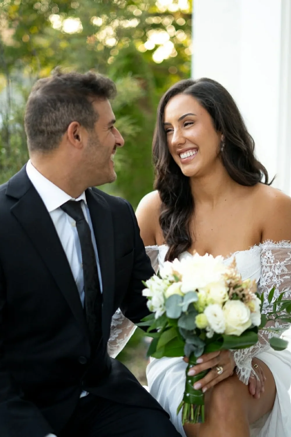 Bride laughing with her groom, bouquet in hand, tanned by GLOW17